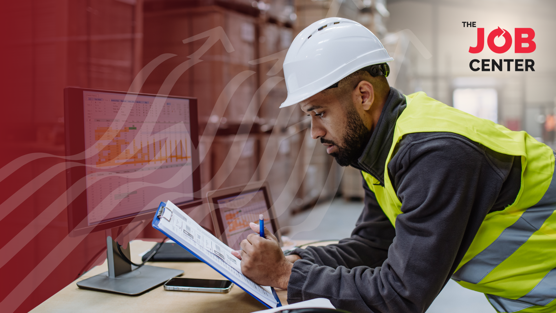 Night shift warehouse worker looks at a clipboard at a desk in the warehouse